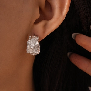 Close-up of minimalist C-shape crinkle earrings with irregular silver lava texture on model