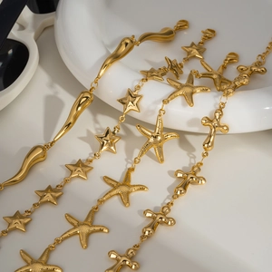Gold stainless steel chain jewelry with starfish, heart, and cross charms on a white plate