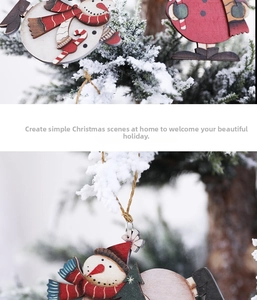 Close-up of wooden snowman ornaments with red scarves hanging on a snow-covered tree