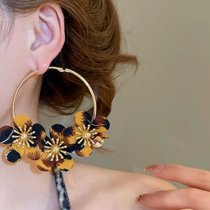 Macro detail of leopard print fabric flower petals on large gold metallic hoop earring