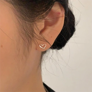 Close-up of minimalist silver heart-shaped stud earring worn on the earlobe