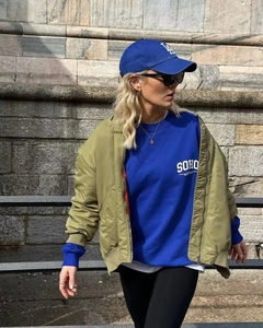 Streetstyle-Ansicht einer olivgrünen Bomberjacke kombiniert mit einem blauen SOHO-Sweatshirt