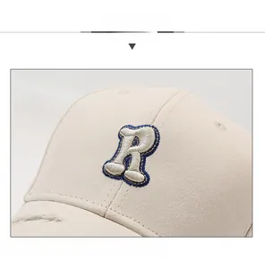 Detail of R letter embroidery and distressed brim on beige cotton baseball cap