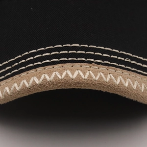 Detailed close-up of a baseball cap brim featuring black twill and khaki suede edging