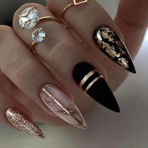 Detail of almond press-on nails with black marble, gold foil, and glitter accents
