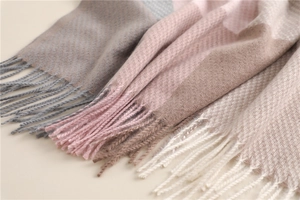 Close-up of fringe details and texture of plaid cashmere scarf in grey pink and beige