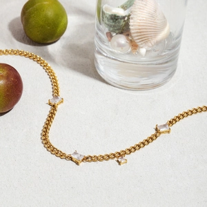 Detailed view of 18K gold plated stainless steel necklace with zircon on beach sand