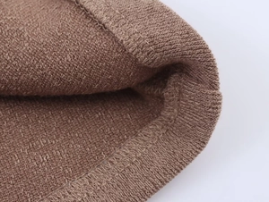 Primer plano macro de tejido de punto marrón con costuras y textura entrelazada