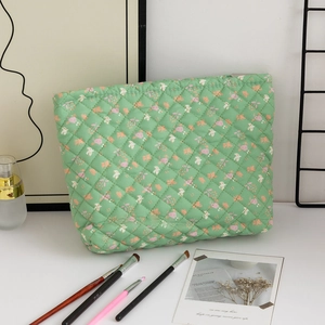 Detail of light green floral quilted makeup bag with pink flowers and a smooth zipper