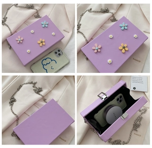 Macro detail of purple square bag featuring 3D floral decorations and metal chain strap