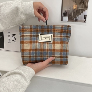Detailed shot of the blue and orange plaid wool makeup bag with a stitched woven label
