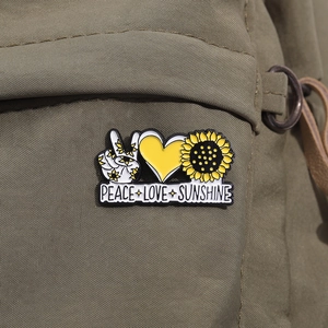 Gros plan d'un pin's émaillé Peace Love Sunshine sur un sac à dos en toile