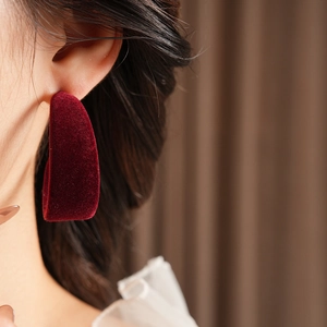 Close-up of a large dark red velvet C-shaped hoop earring worn for a stylish fashion look