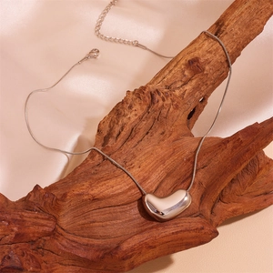 Silver stainless steel heart pendant snake chain necklace on rustic wood and silk