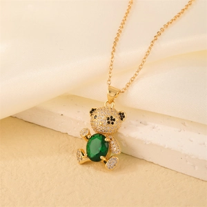 Detail of golden bear pendant necklace featuring green oval gem and micro pave zircons