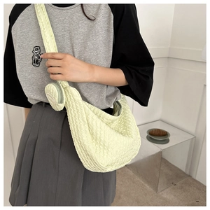 Detail view of yellow seersucker crossbody bag with a round mini pouch and textured surface