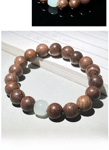 Détail macro de perles en bois de santal naturel avec une perle d'accent en jade blanc