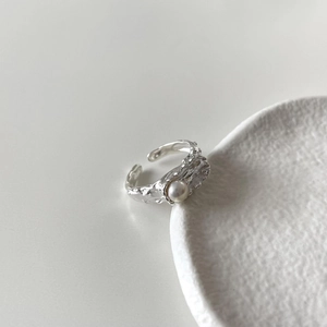 Detail of irregular silver ring featuring textured surface and elegant pearl inlay
