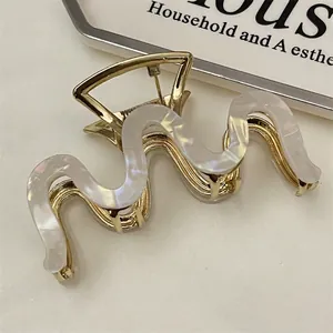 Close-up of golden wavy claw clip with pearlescent marble texture and French vintage style