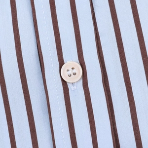 Macro d'une chemise en popeline rayée montrant un bouton beige et la texture du tissu fin