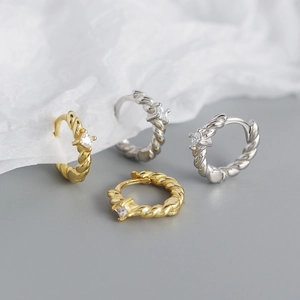 Detailed close-up of gold and silver twisted hoop earrings with square cubic zirconia