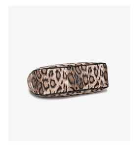 Detail view of the oval base on leopard print crescent bag with black piping trim