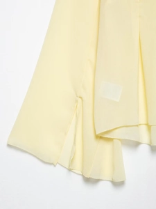 Détail du haut en mousseline jaune pâle avec fente latérale et ourlet multicouche