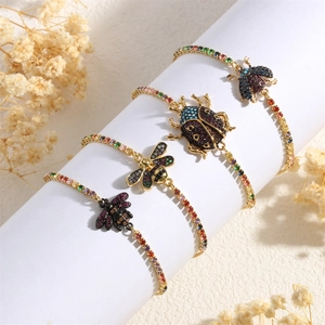 Detail view of four gold-plated insect bracelets with colorful gems on a white stand