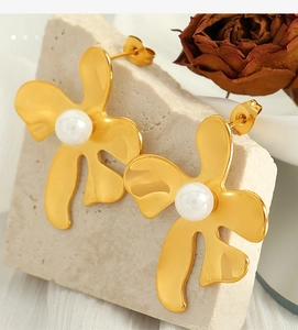 Détail de boucles d'oreilles fleurs dorées avec perles blanches sur pierre