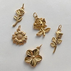 Dettaglio di cinque ciondoli a fiore in acciaio inossidabile dorato per gioielli DIY