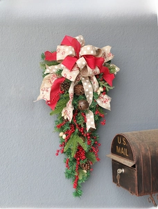 Detail of Christmas teardrop swag with red berries, pine cones and burlap bow