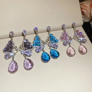 Three pairs of crystal butterfly teardrop earrings in purple, blue, and pink on a jewelry box