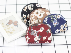 Detail of four floral canvas coin purses with zippers on a grid background