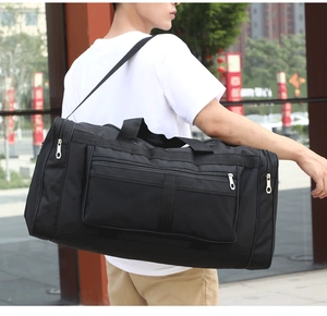 Man carrying a black canvas travel bag with multiple pockets in an outdoor street setting