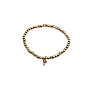 Detailed shot of a gold beaded bracelet with a colorful zircon letter P pendant