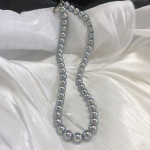 Detail of silver-blue round pearl necklace with colorful luster on white satin fabric