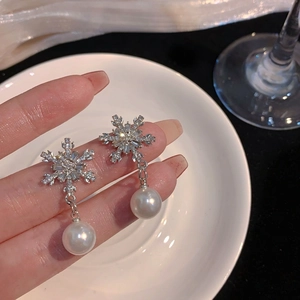 Detailed view of silver snowflake drop earrings with crystals and white faux pearls