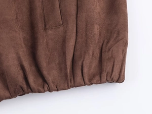 Detail of dark brown suede jacket featuring elastic hem and soft micro-texture