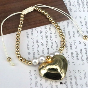 Close-up of handmade beaded bracelet with gold beads, pearls and 26mm heart pendant