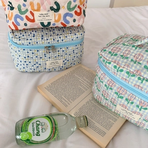 Three quilted cotton cosmetic bags with floral and geometric patterns on white linen
