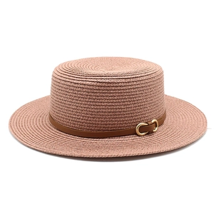 Détail d'un chapeau de paille rose avec bande en cuir brun et boucle mors dorée