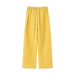 Close-up of yellow quilted wide-leg trousers with elastic waistband and detailed stitching