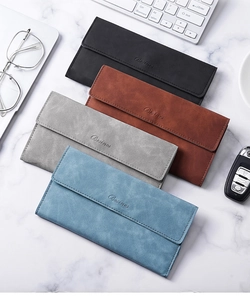 Flat lay of four matte leather wallets in black, brown, gray, and blue on a marble surface