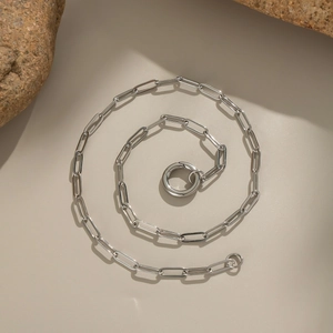 Macro shot of silver stainless steel paperclip chain necklace on stones background
