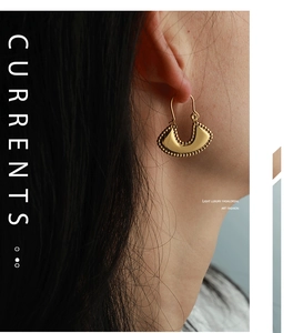 Close-up of vintage gold-plated U-shaped earrings with fine beaded edge on ear