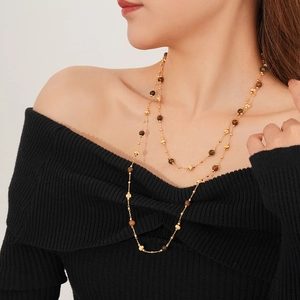 Close-up of gold-plated tiger eye layered necklace on model wearing black sweater