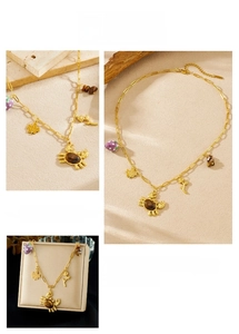 Detailed view of gold crab pendant with tiger eye stone and maple leaf charms