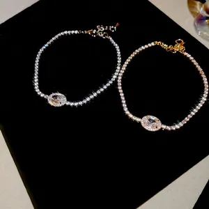 Elegant silver and gold oval zircon tennis bracelets with halo design on black velvet