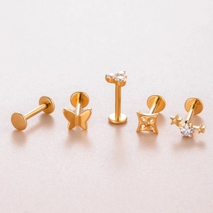 Macro view of gold titanium labret studs featuring butterfly star and crystal shapes
