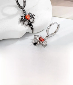 Detailed view of gothic wing earrings with red heart zircon in silver and black copper